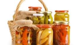 Composition with wicker basket and jars of pickled vegetables.